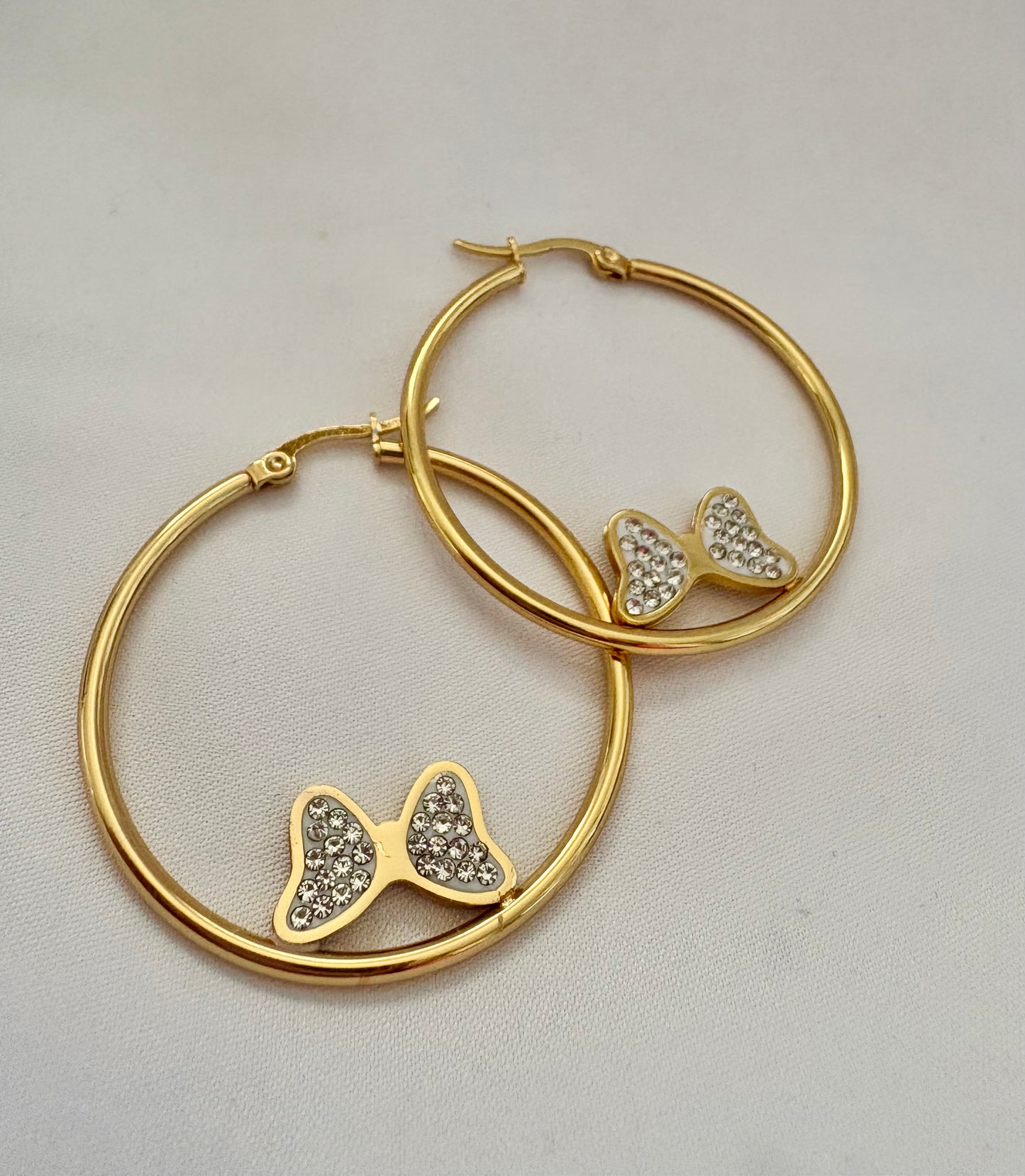 Gold hoop earrings with butterfly-shaped charms on a light background