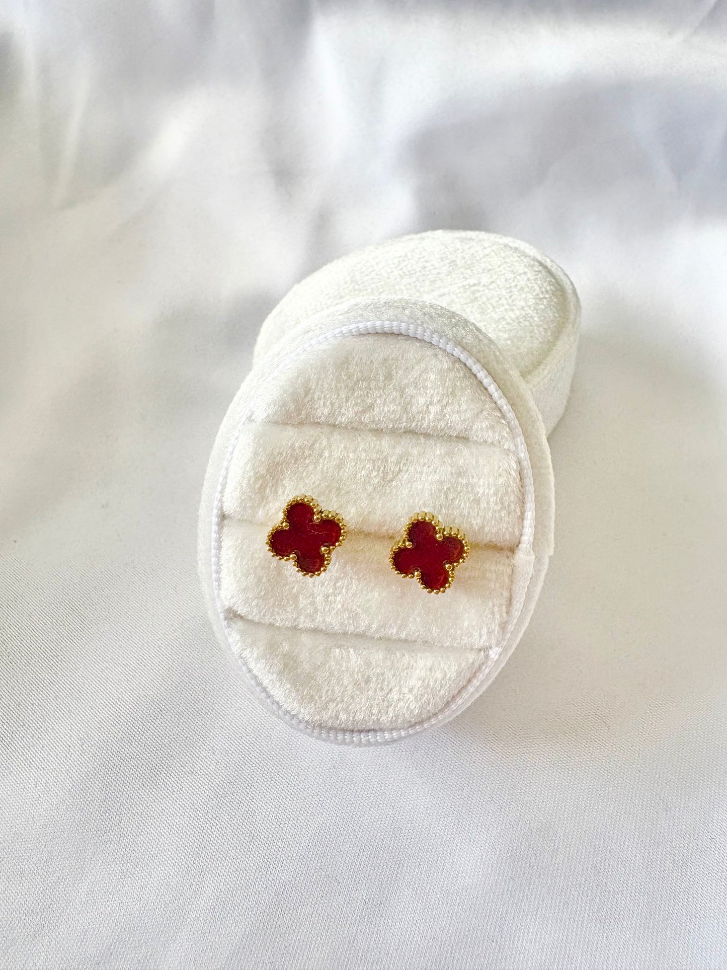 Pair of red wine clover earrings in a white jewelry box on a white background