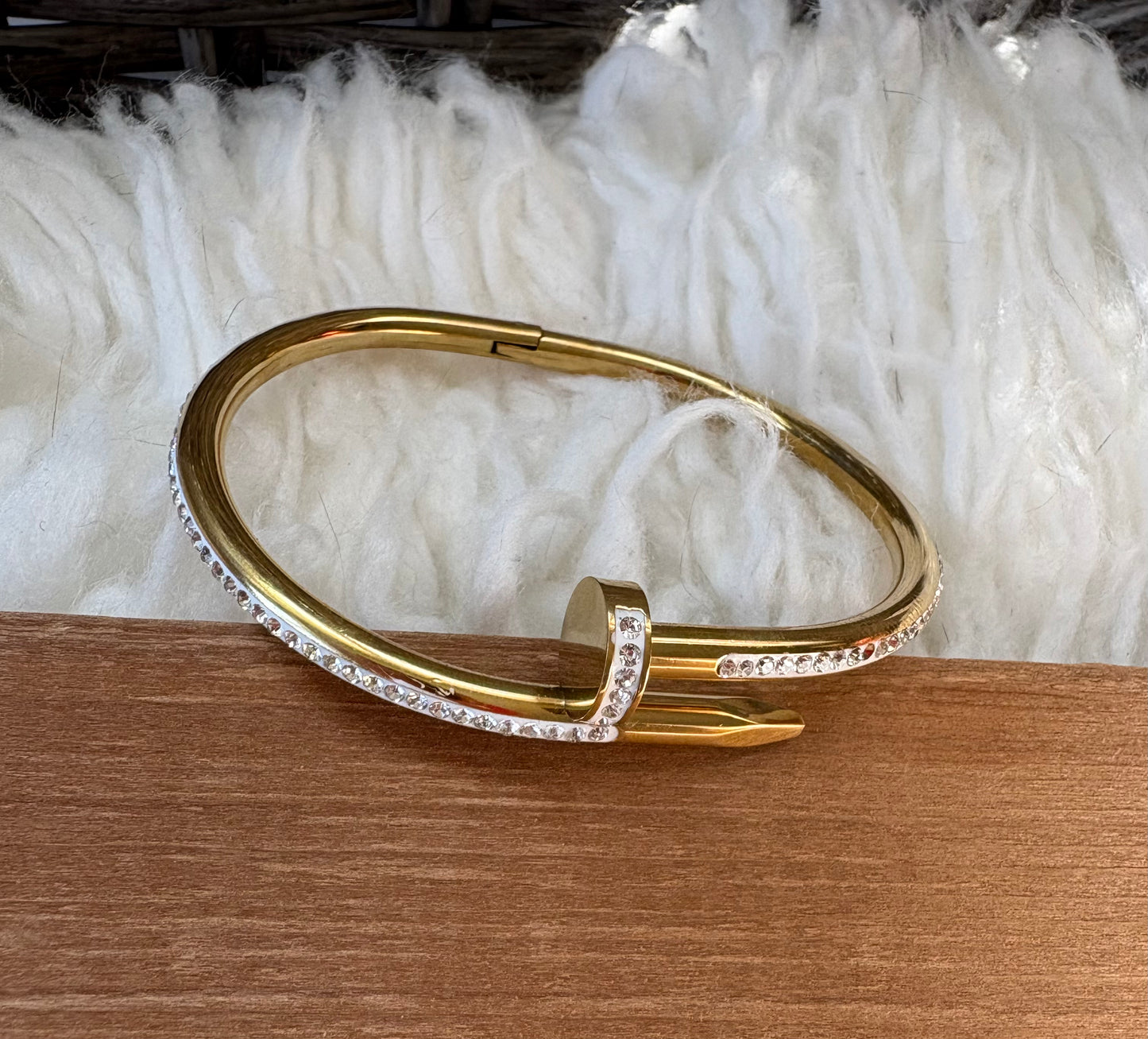 A gold-toned bracelet with a row of zircon stones along the front band.
