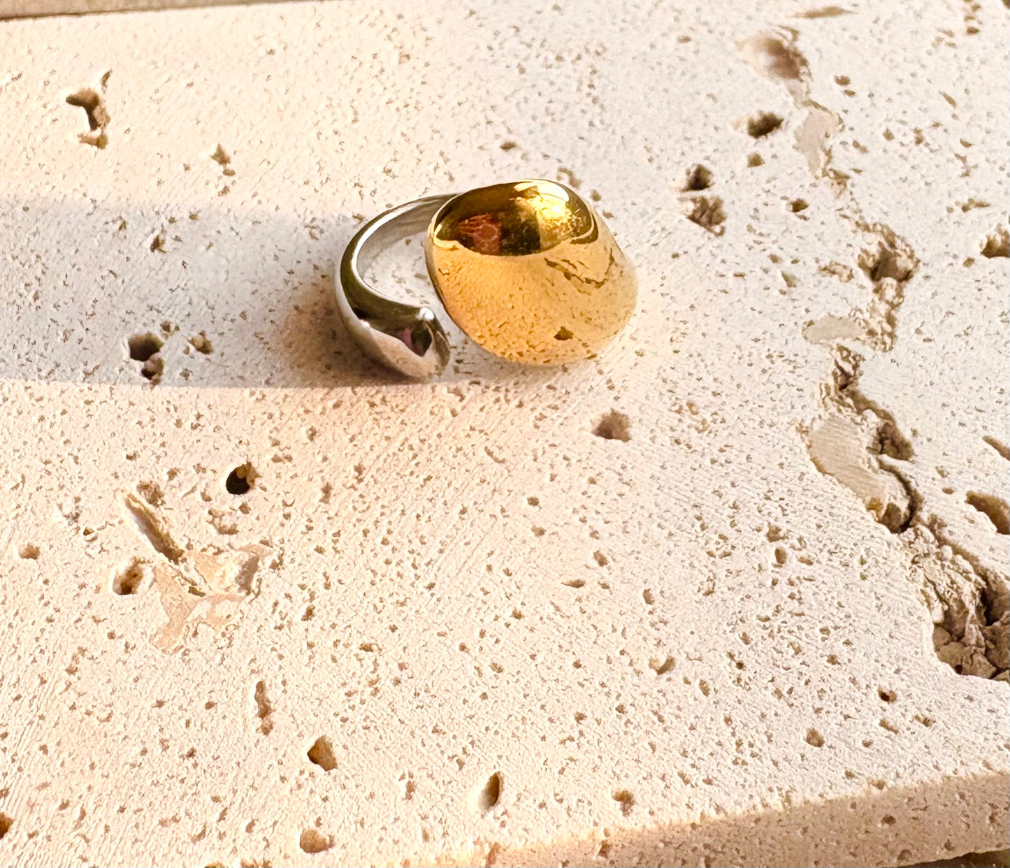 Two-tone abstract dome ring with silver band and gold dome accent on textured background