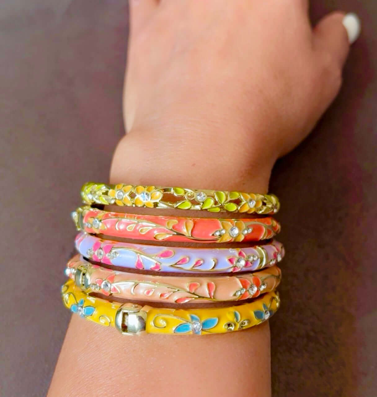 Hand wearing multiple colorful bracelets on a blurred background