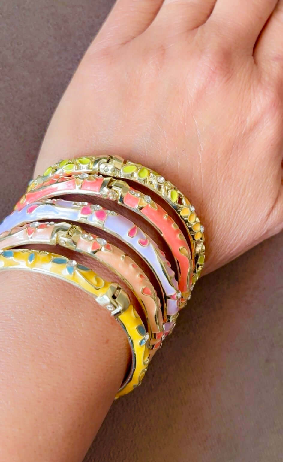 Close-up of a wrist wearing colorful bangles on a neutral background
