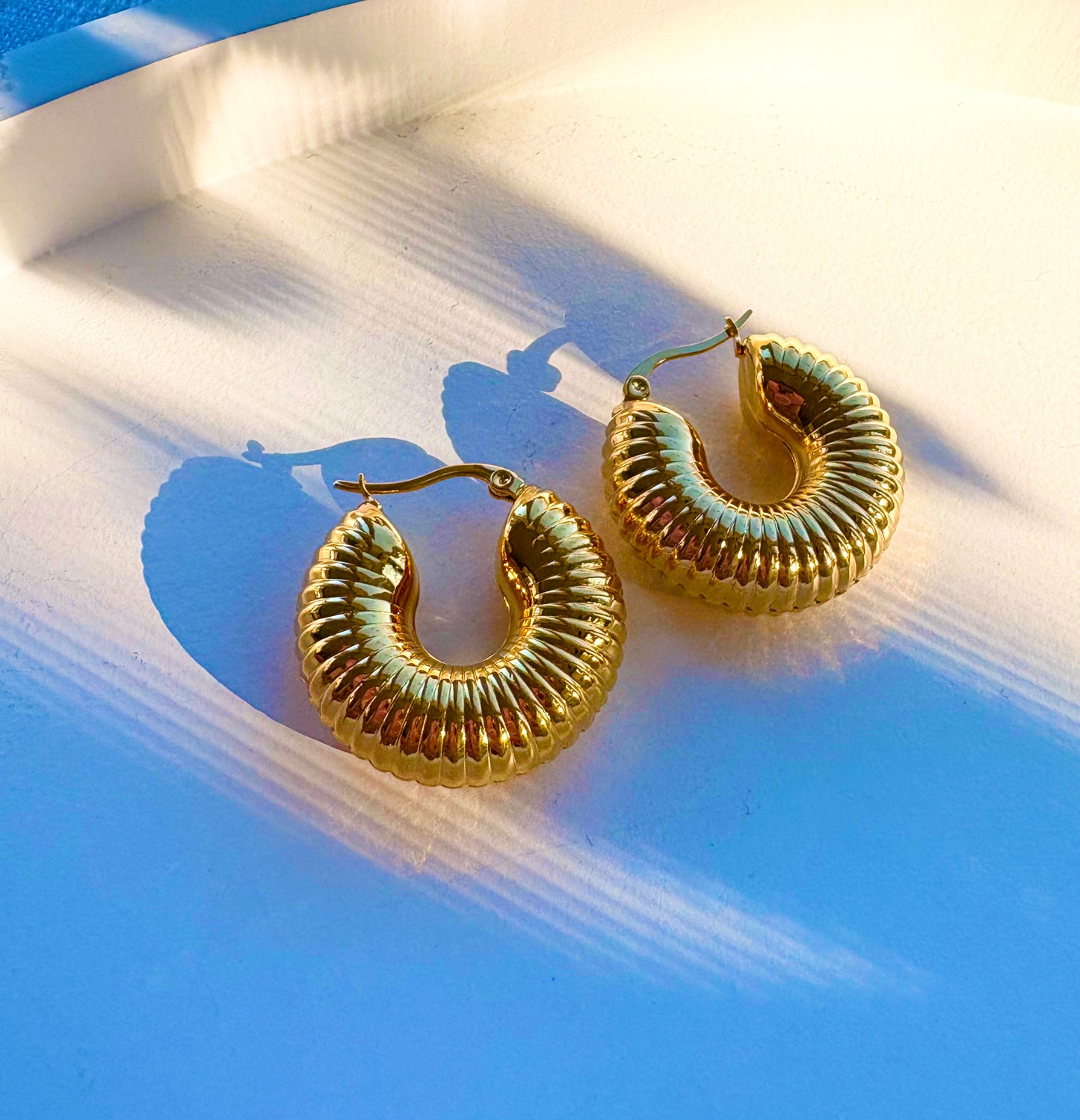 Close‑up of a ridged gold hoop earring highlighting its grooved, ribbed pattern
