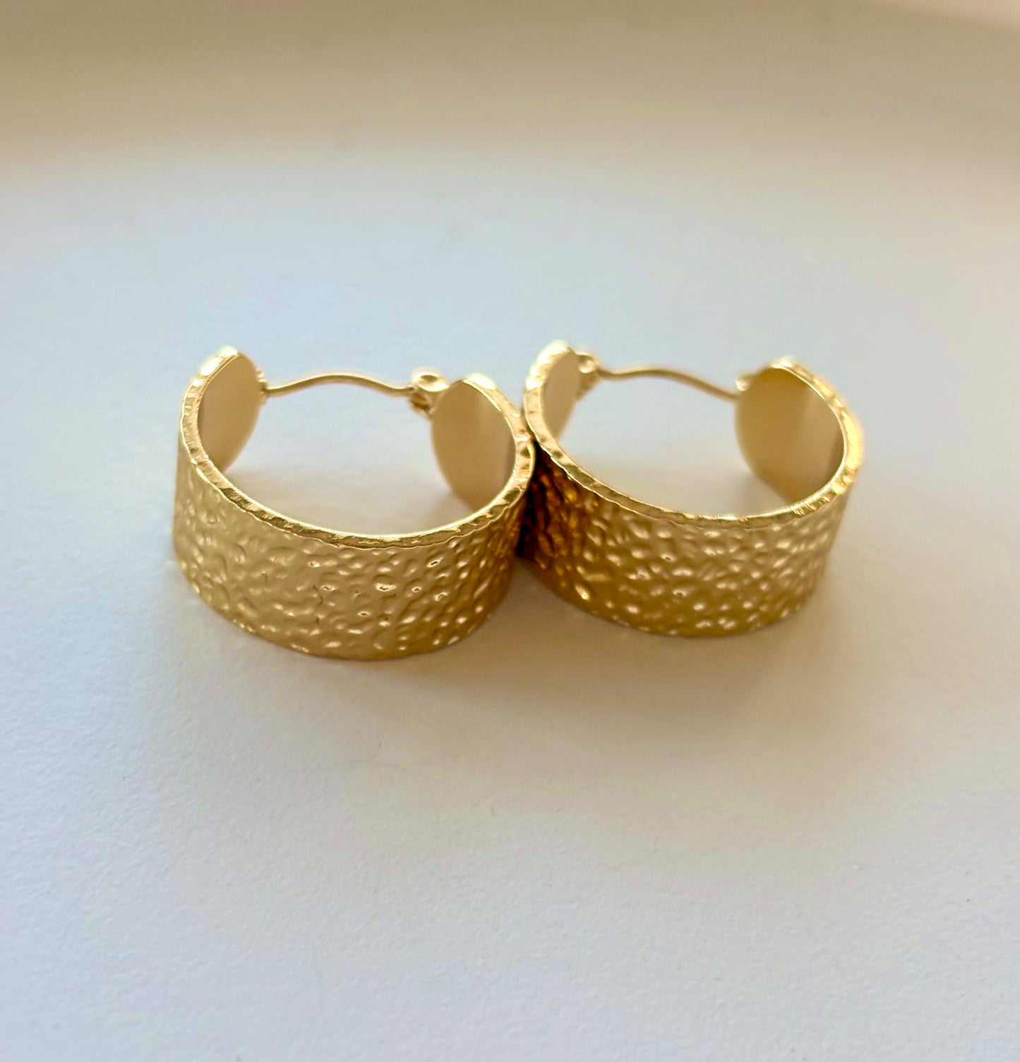 Pair of gold hoop earrings on a light background