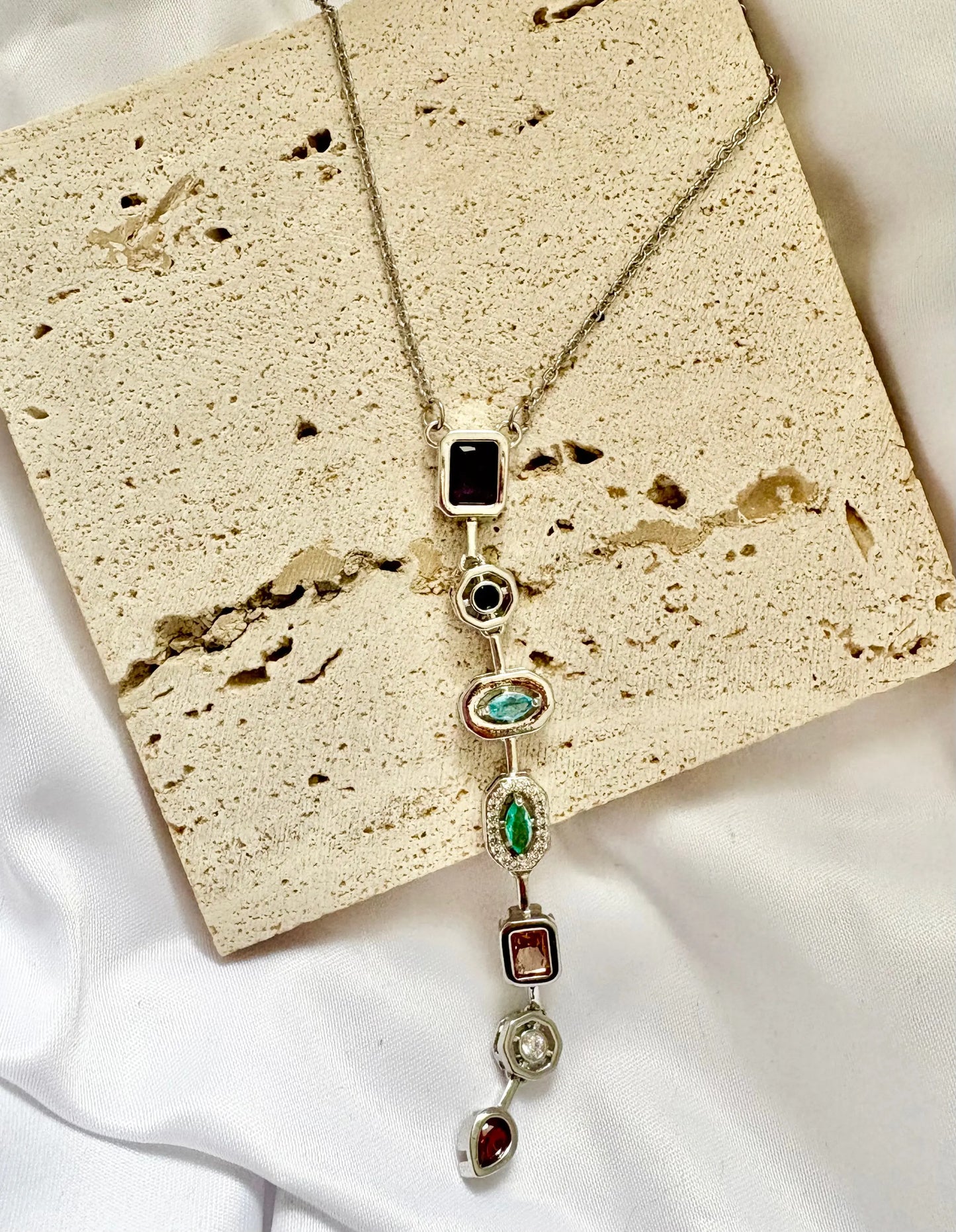 Necklace with gemstones on a textured beige surface