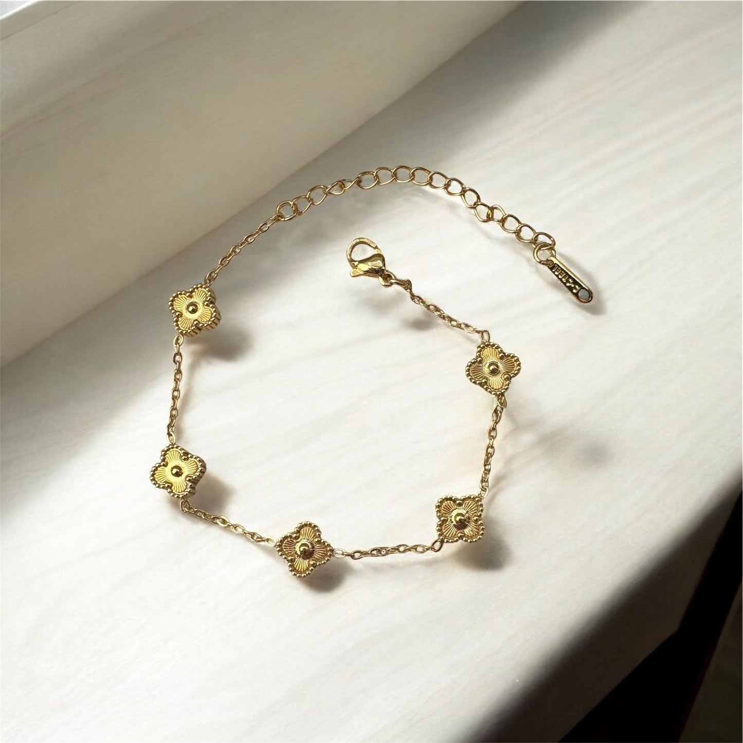 Gold bracelet with floral designs on a light background