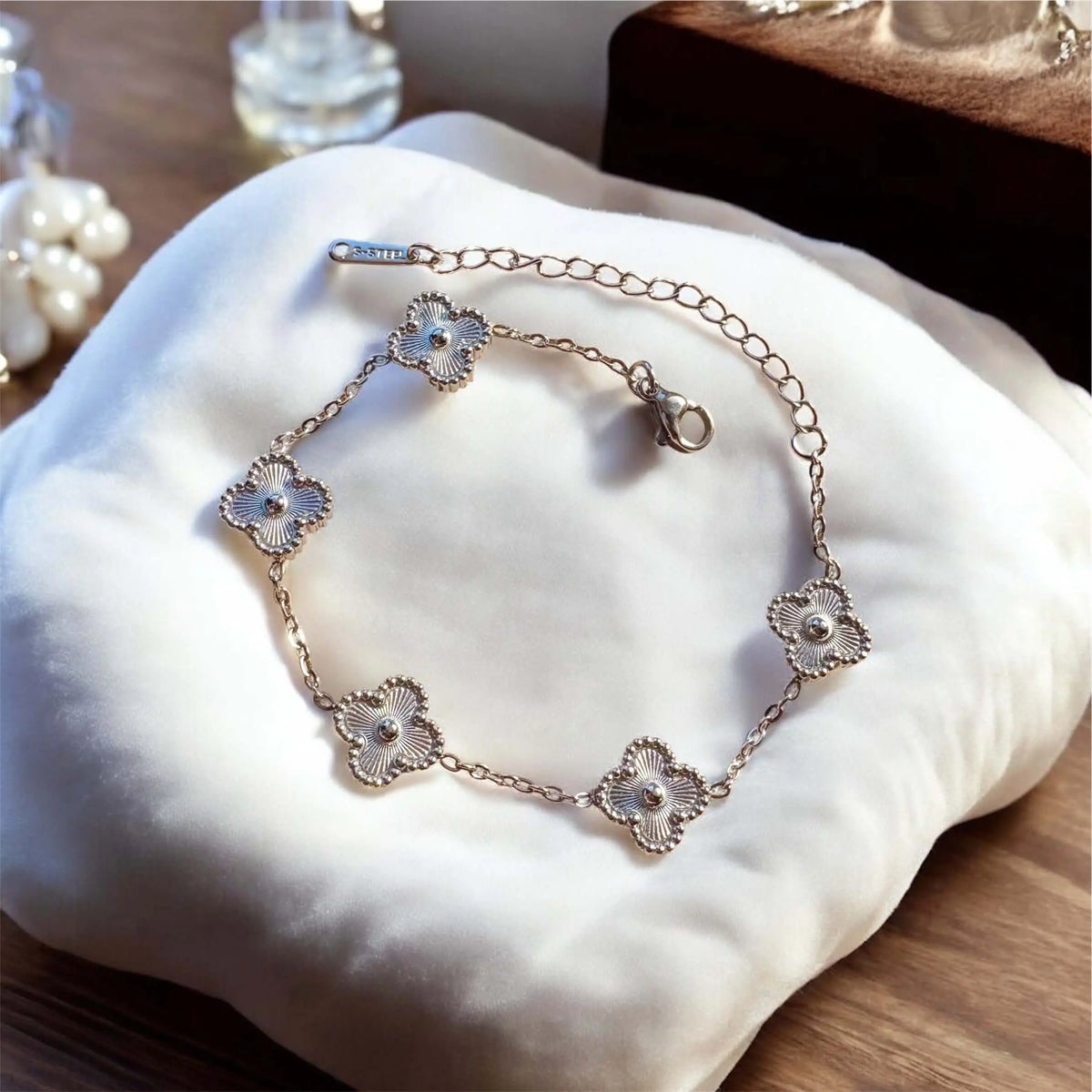 Silver bracelet with floral designs on a white cushion