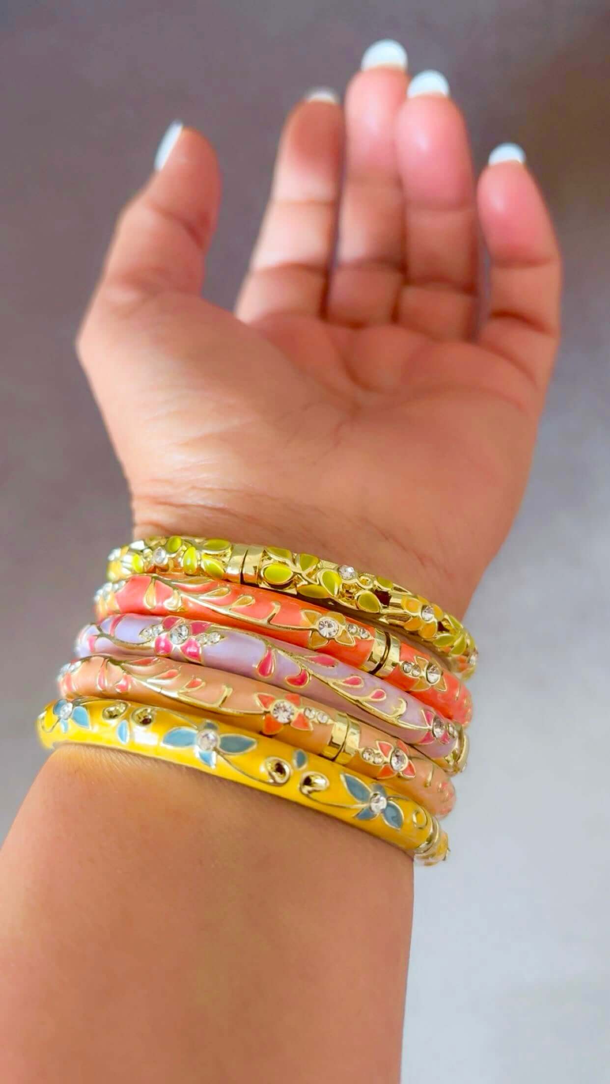 Hand wearing colorful bracelets on a neutral background