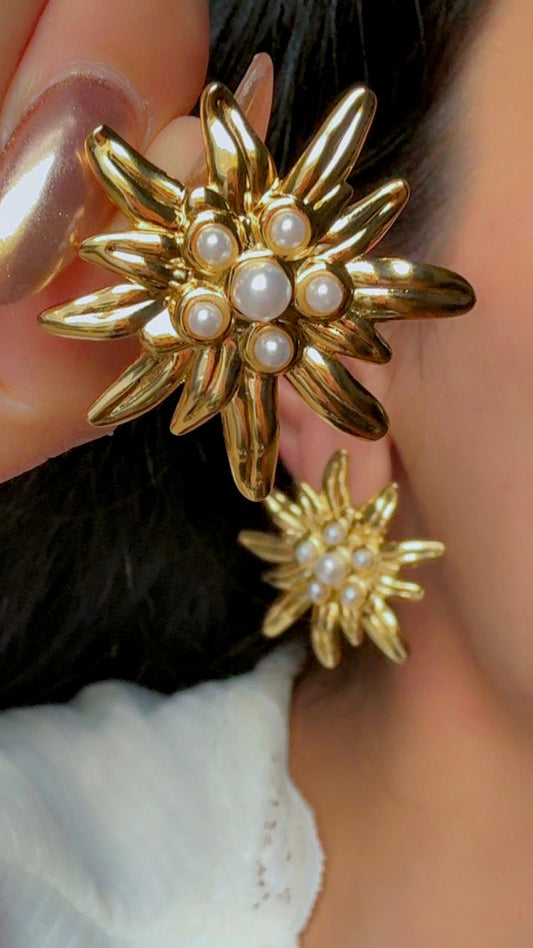 Gold flower statement earrings with pearl accents displayed on ear