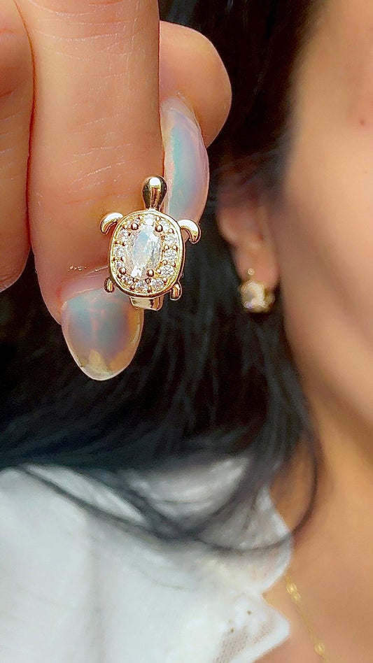 Turtle stud earrings with sparkling oval crystal center displayed on ear