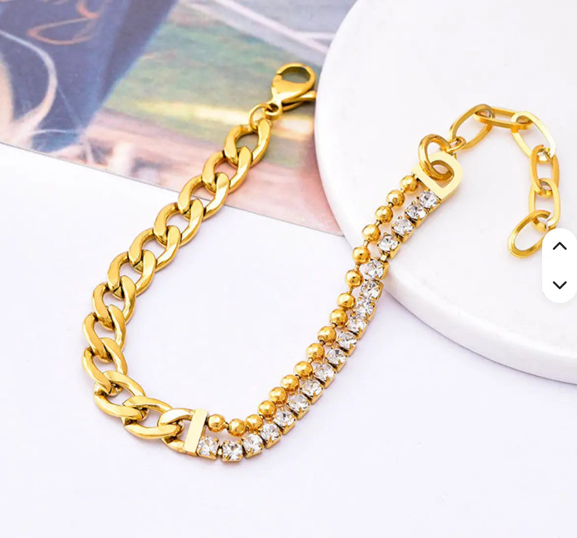 Gold-tone bracelet with curb-chain links, clear sparkling stones, bead details and a lobster clasp