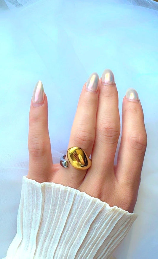 Hand wearing a ring with a gold & silver ring on a light blue background