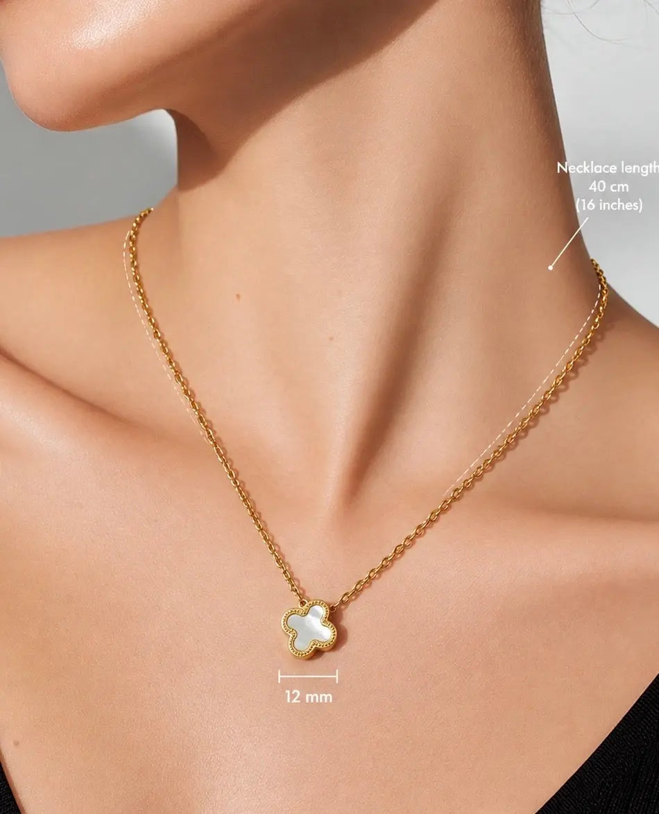 A close-up of a model wearing a delicate gold chain necklace with a small clover-shaped pendant