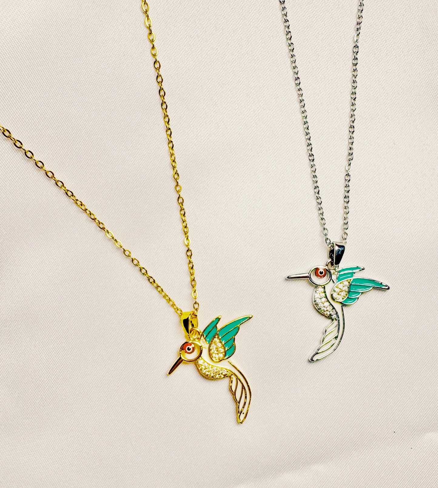 hummingbird pendants on gold and silver chains against a light background
