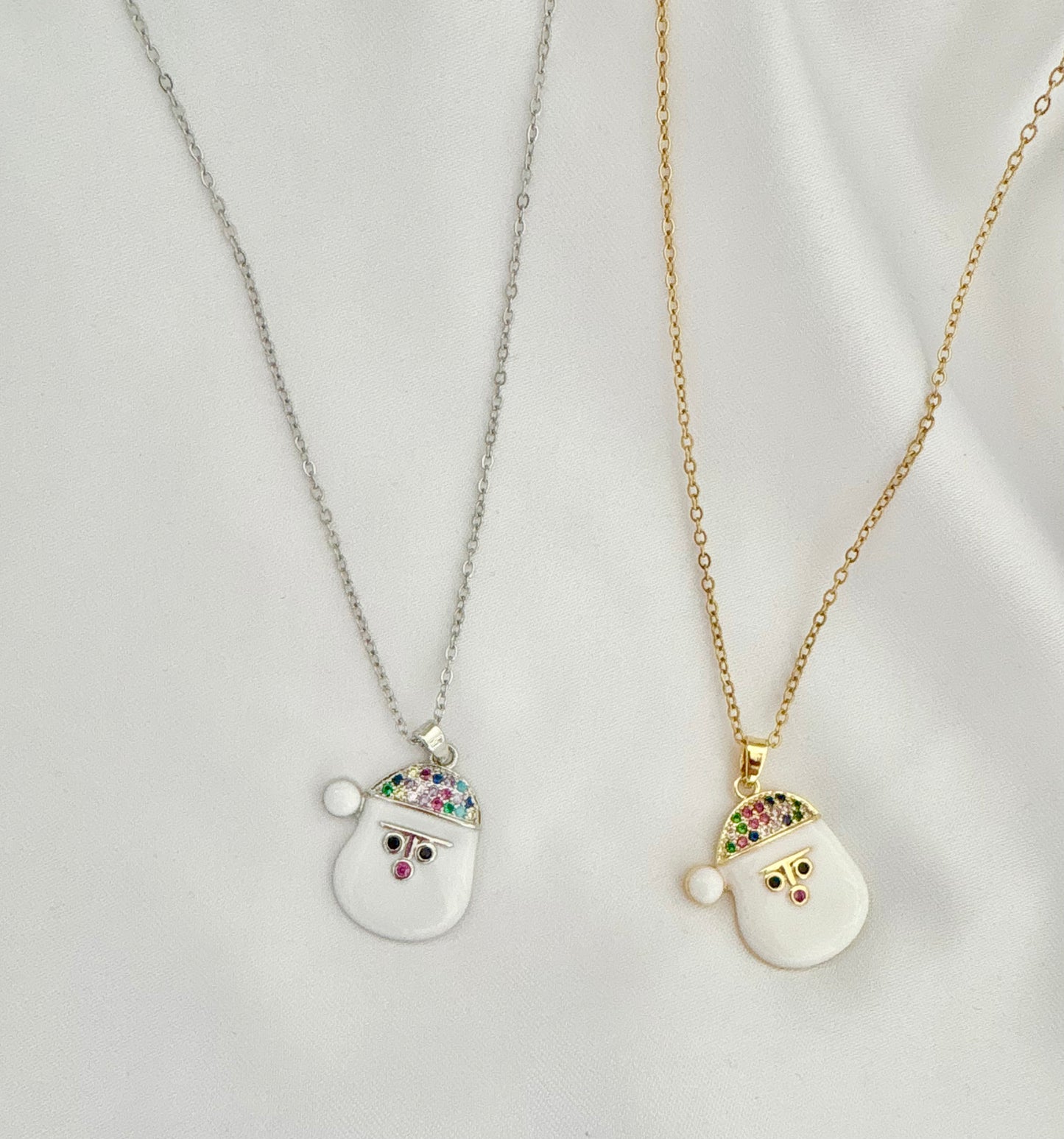 Two Santa Claus pendants on gold and silver chains against a light gray background.