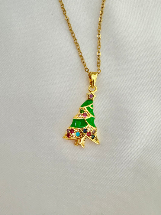 Gold necklace with a green Christmas tree pendant on a light gray background.