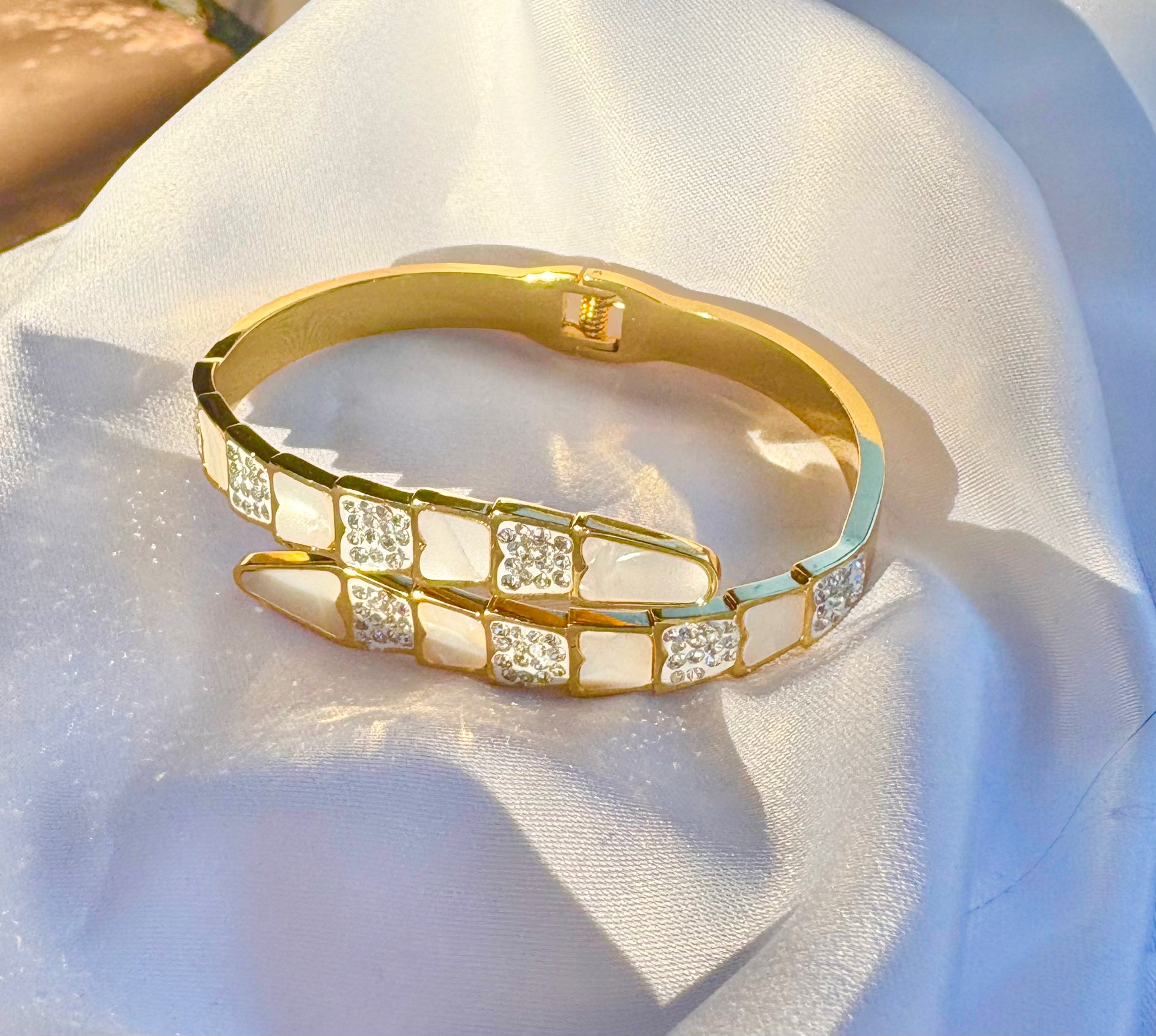 Gold bracelet with zircon accents on a white fabric background