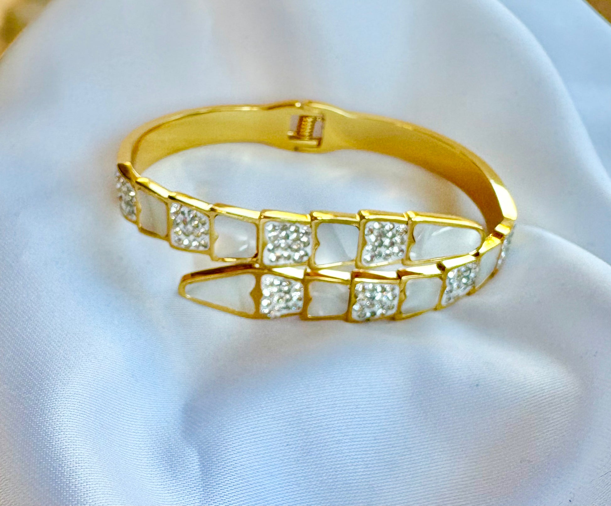 Gold bracelet with embedded stones on a white fabric background