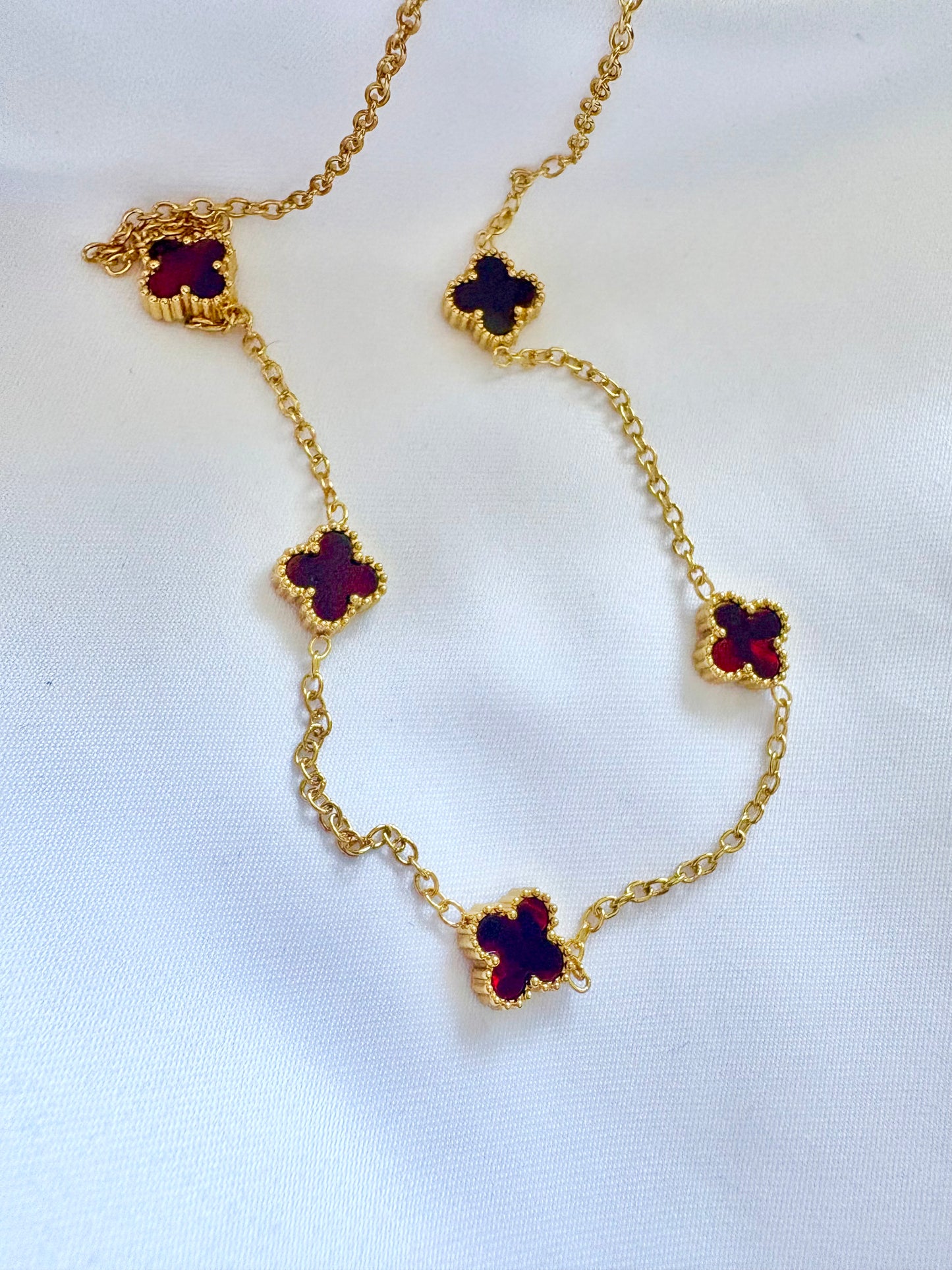 Gold necklace with clover-shaped pendants on a white background