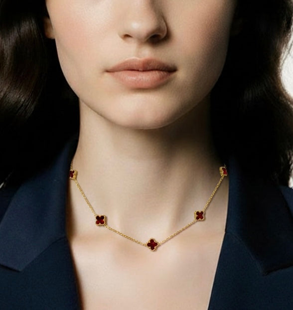 Close-up of a woman wearing a gold necklace with red wine clovers.