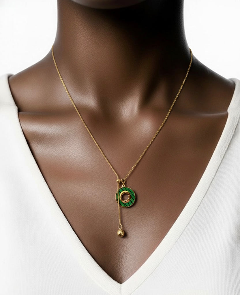 Mannequin wearing a gold necklace with a green pendant on a white background