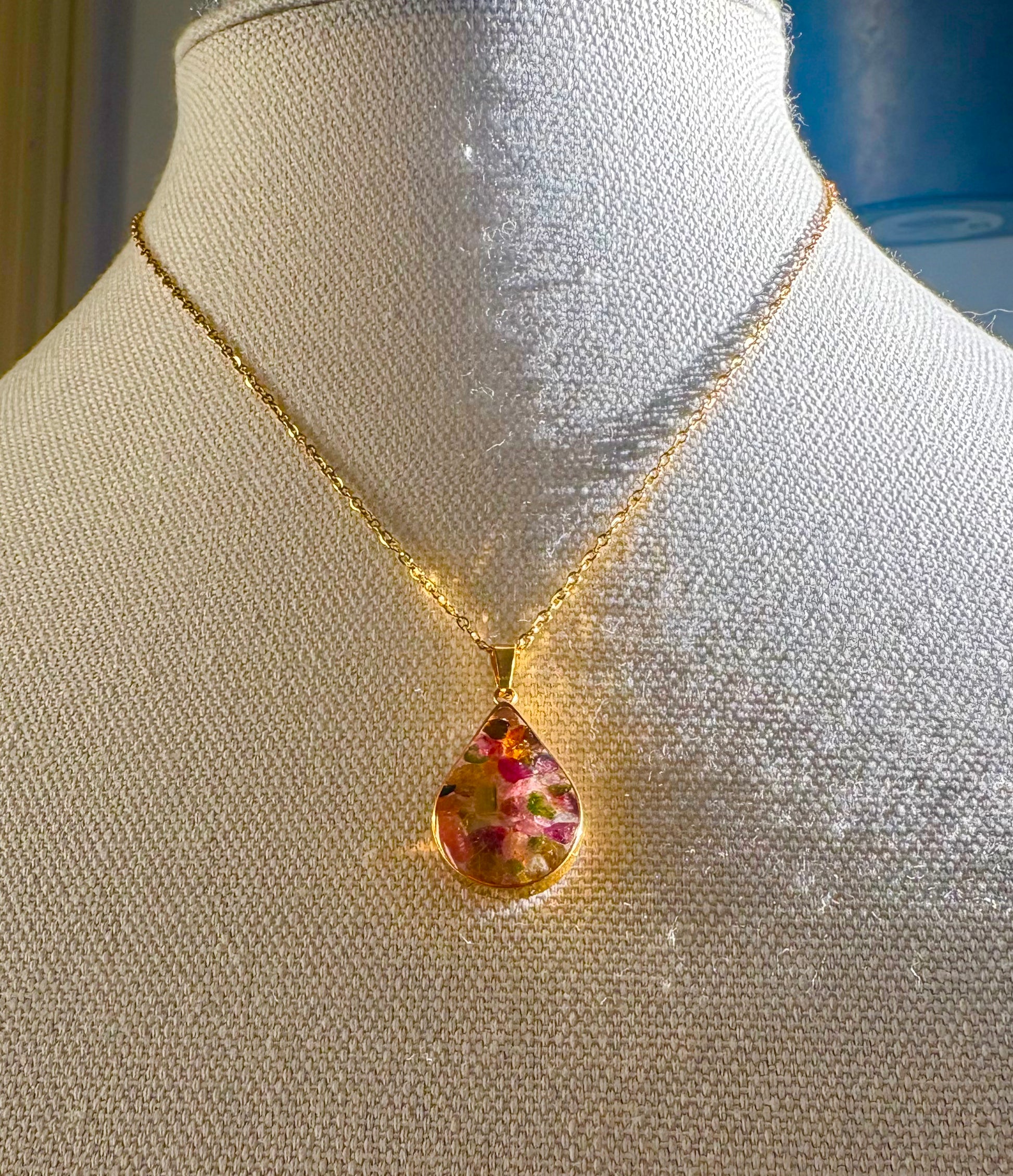 Gold necklace with a floral pendant on a mannequin bust.