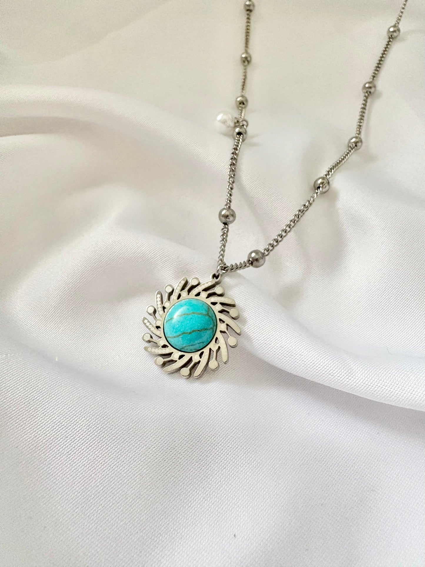 Necklace with a turquoise pendant on a white fabric background