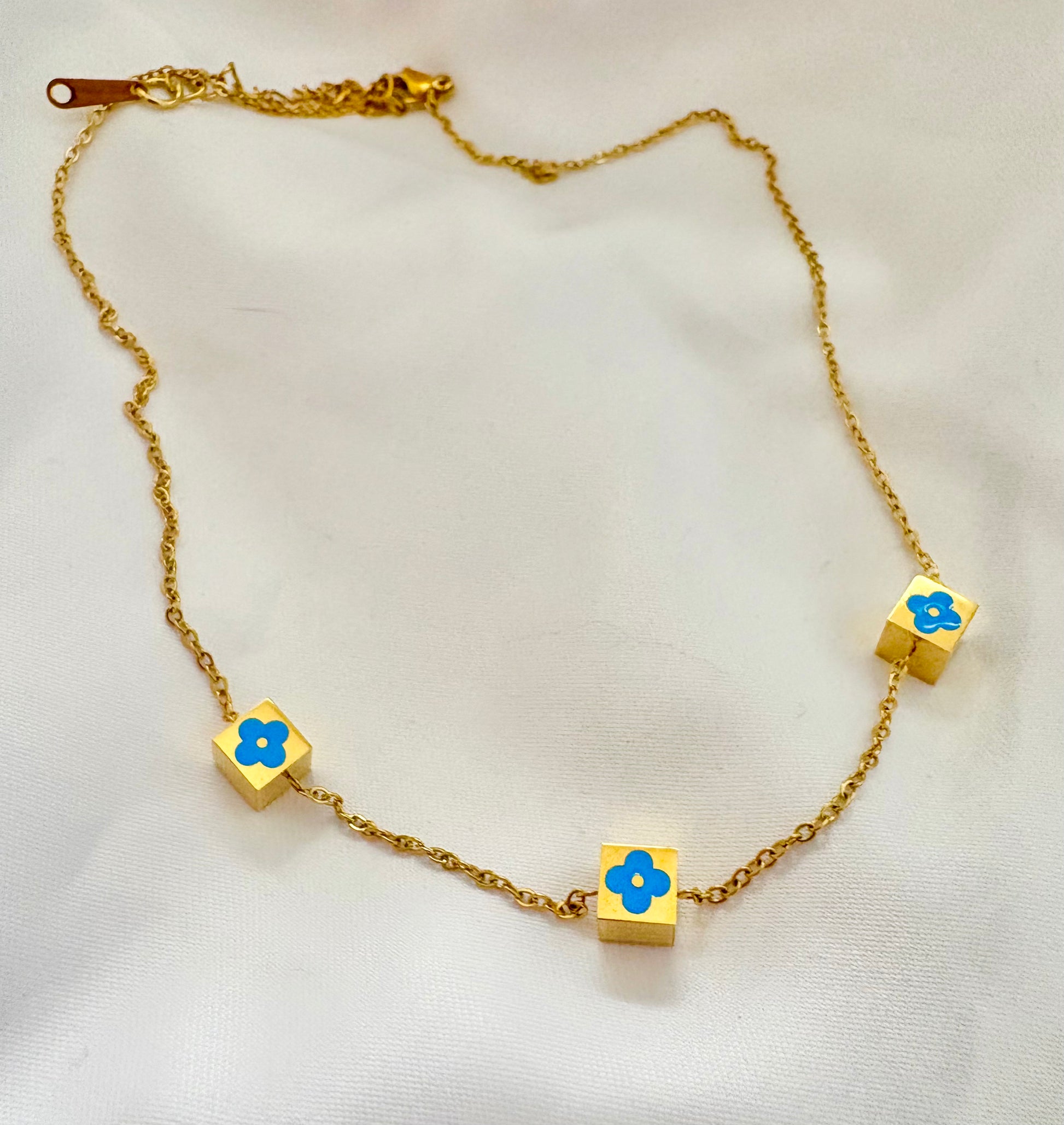 Gold necklace with blue flower pendants on a white background