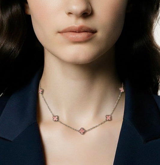 Necklace with pink clover pendants worn by a person against a dark background