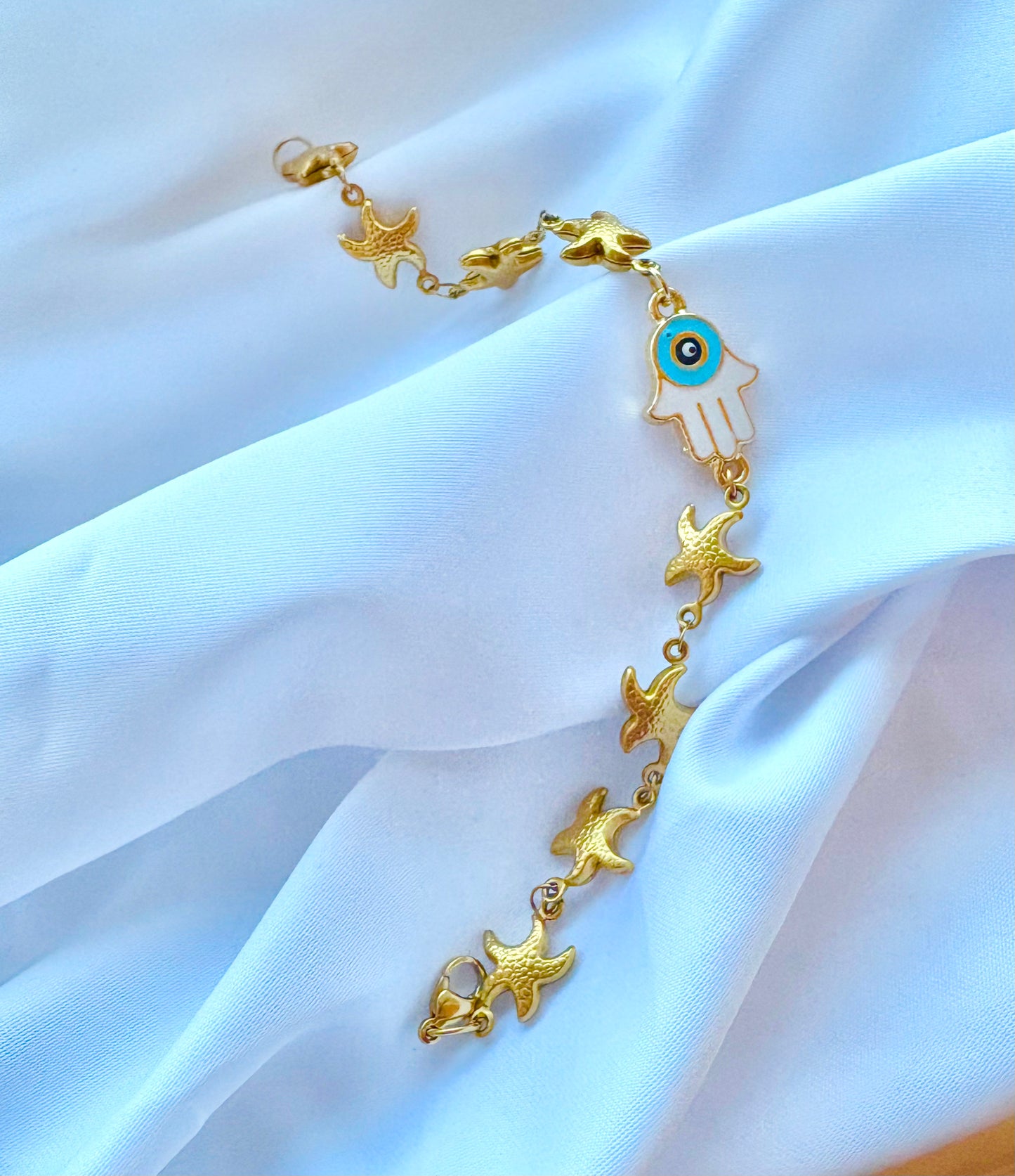 Gold bracelet with blue Hamsa charm and starfish details