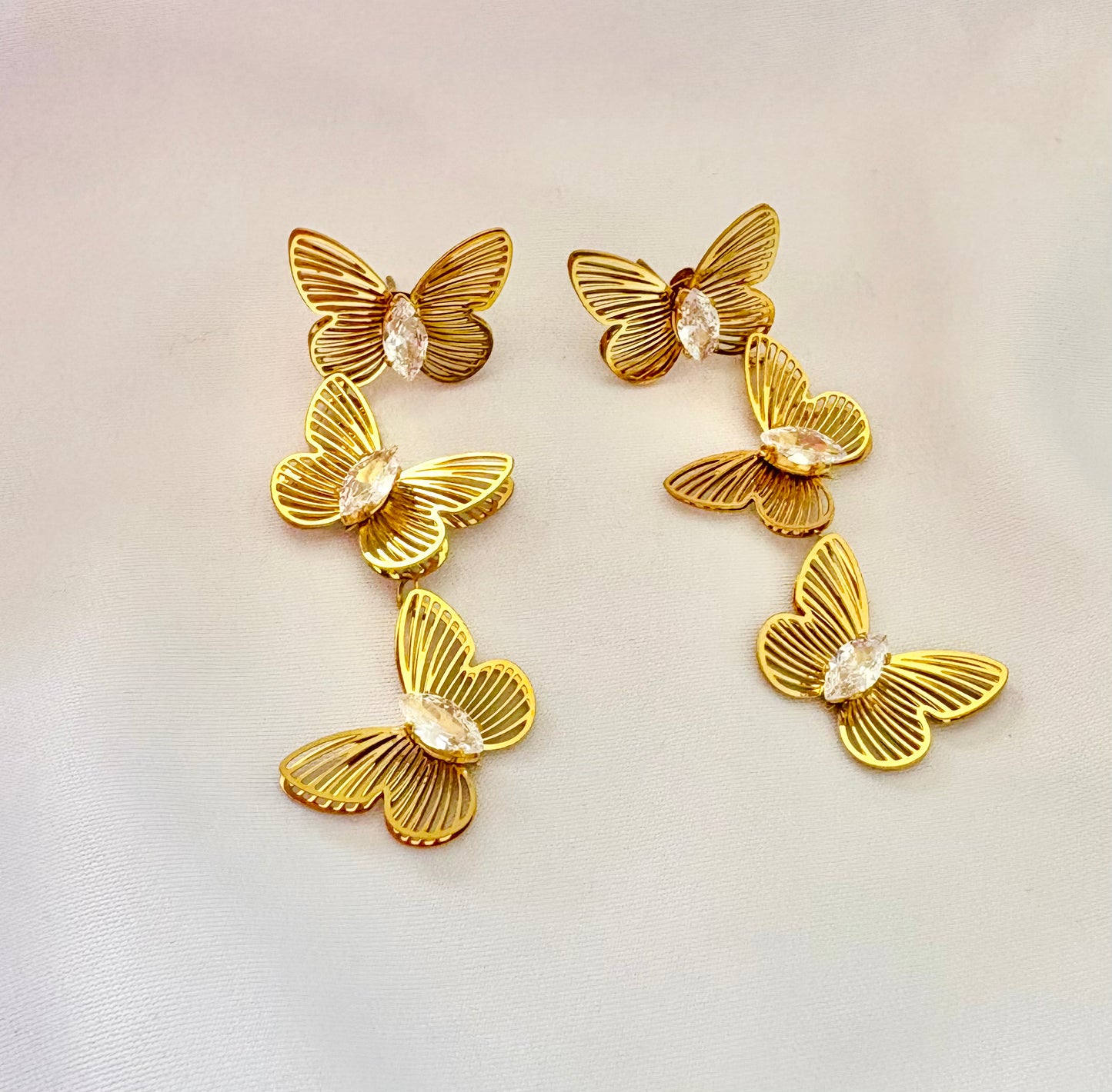 Gold butterfly-shaped earrings on a light background