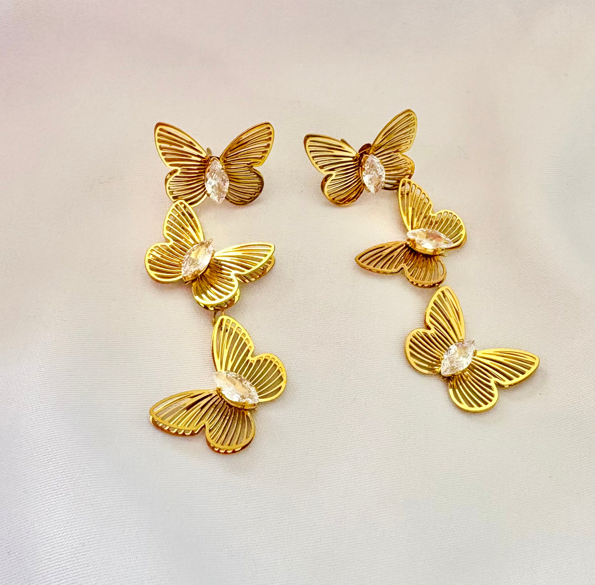 Gold butterfly-shaped earrings on a light background