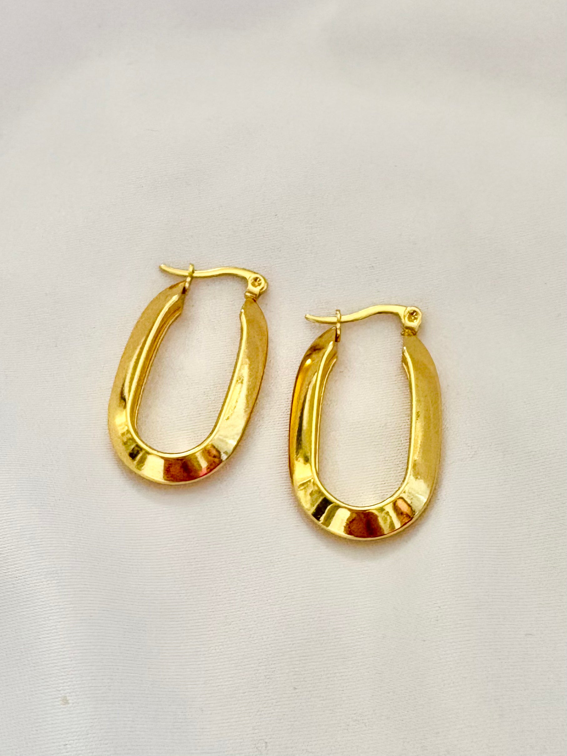 Gold hoop earrings on a light beige background