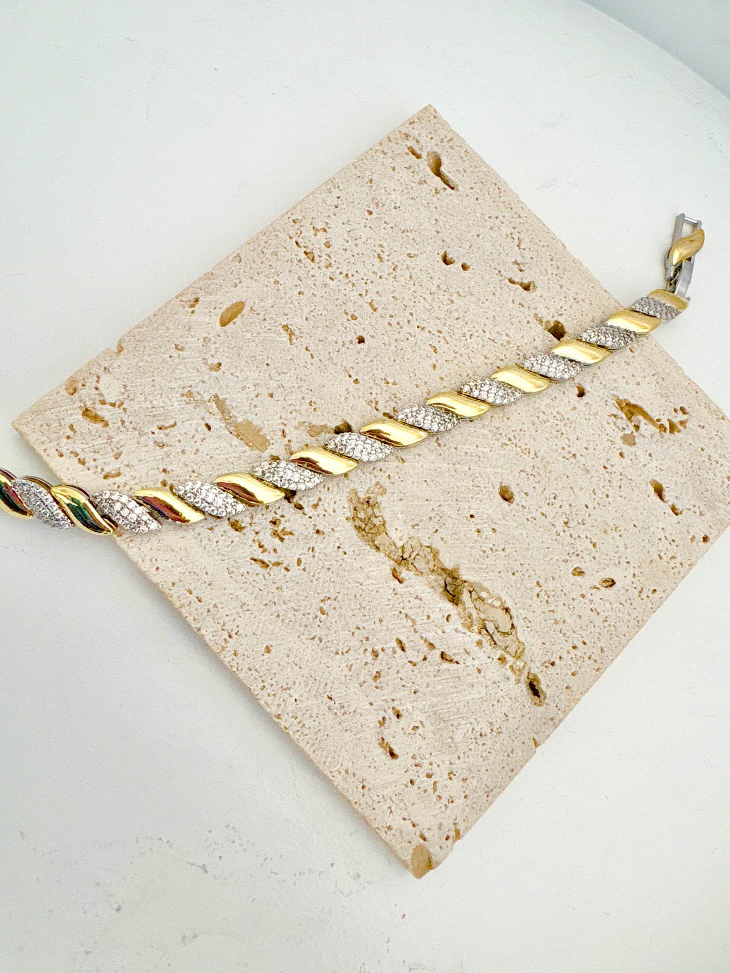 Gold and silver braided bracelet on a textured beige card