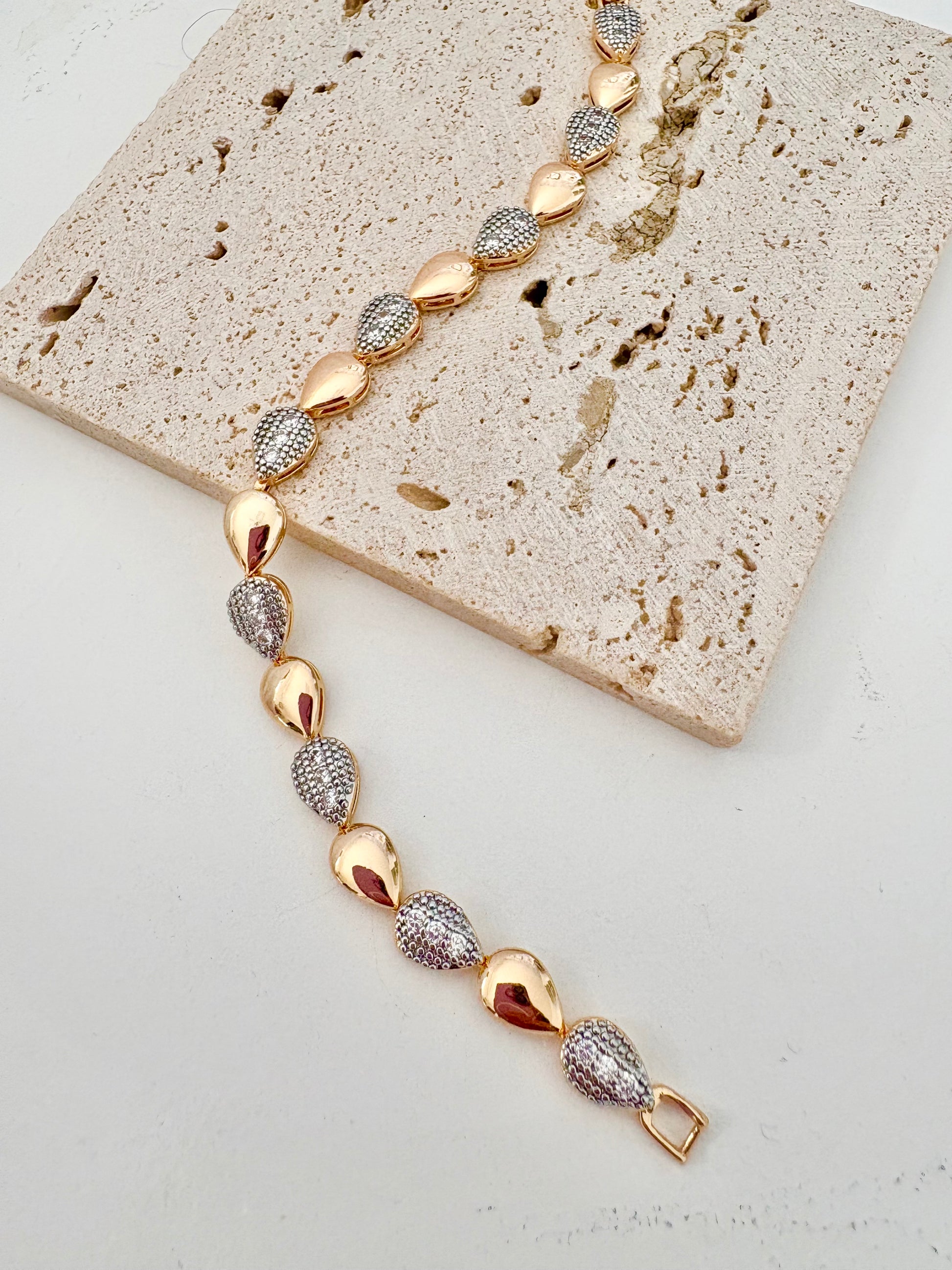 Gold and silver bracelet on a textured stone surface
