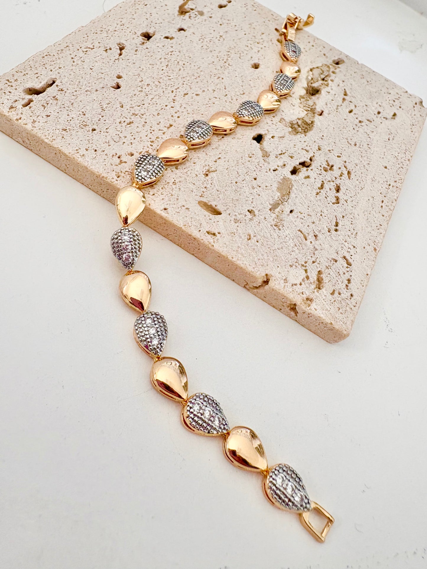 18k Gold plated and silver stainless steel bracelet on a textured stone surface
