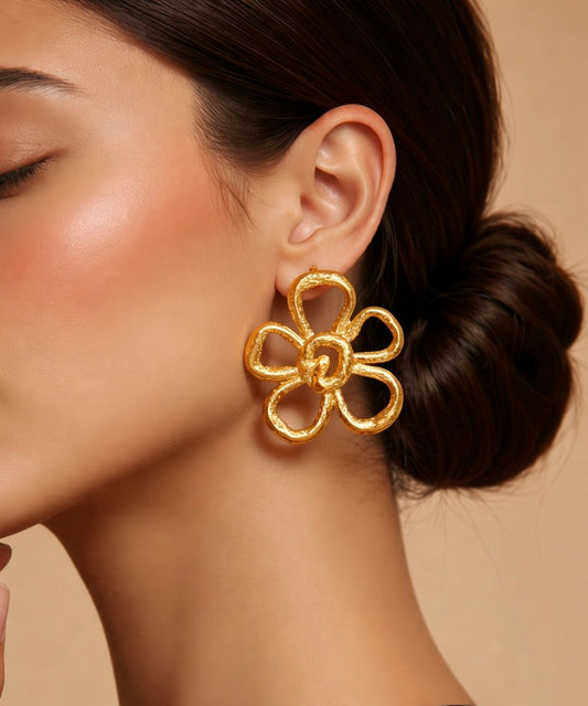 Gold floral earring worn by a model