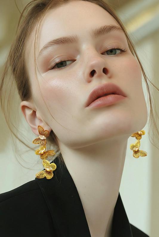 Close-up of a person wearing gold earrings with a neutral background