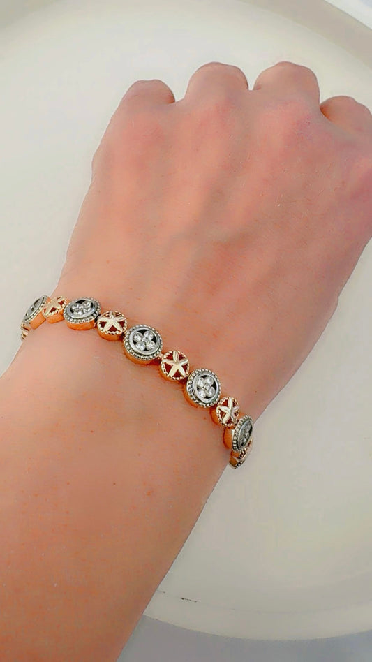 Gold and silver bracelet with zircon stones on a wrist against a white background