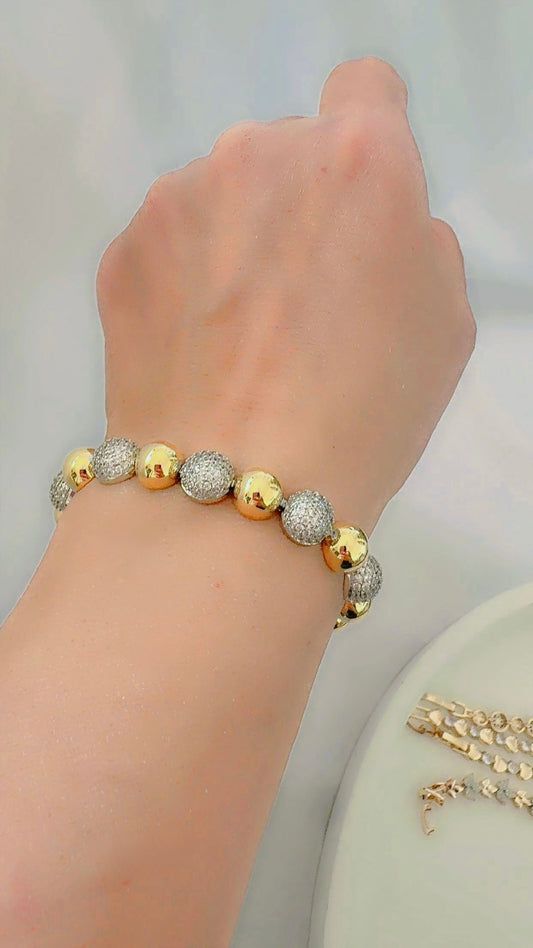 Gold and silver dome bracelet on a wrist with a neutral background
