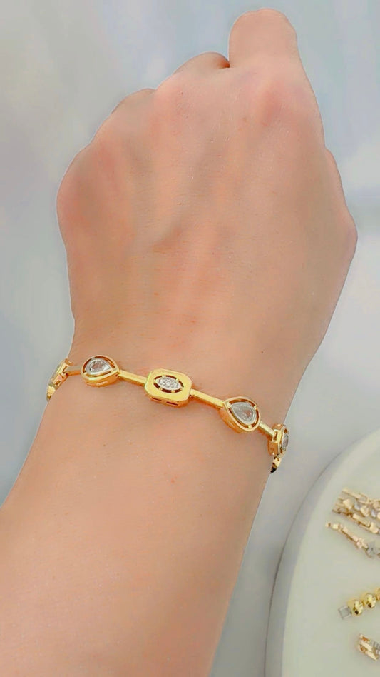 Gold bracelet with zircon stones on a wrist against a light background