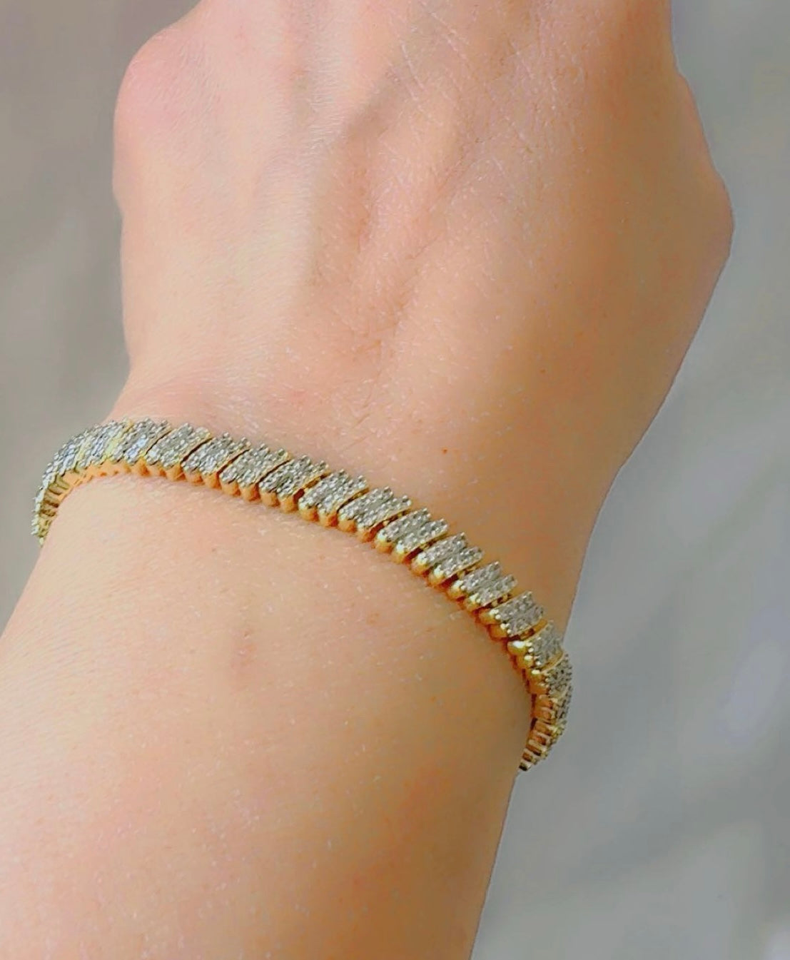 Gold bracelet with zircon on a wrist against a neutral background