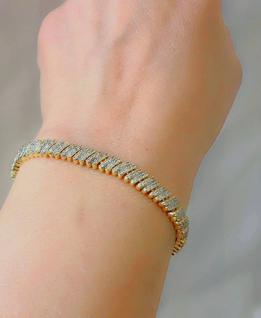 Gold bracelet with zircon on a wrist against a neutral background