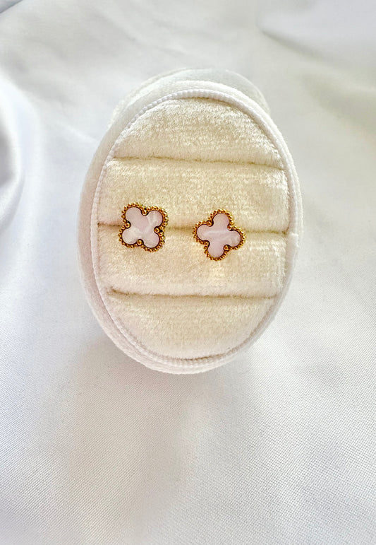 Pair of clover earrings on a white surface with a white box