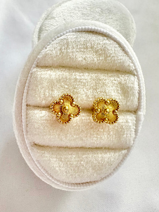 Pair of gold earrings on a white jewelry display