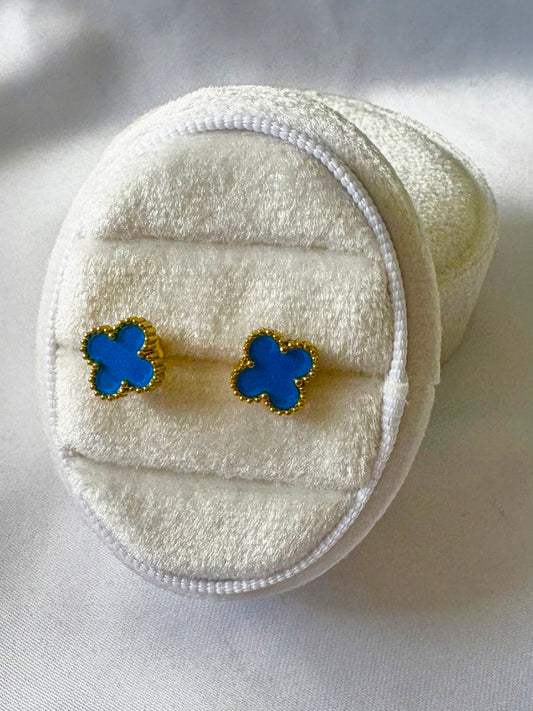 Blue clover earrings on a white textured surface