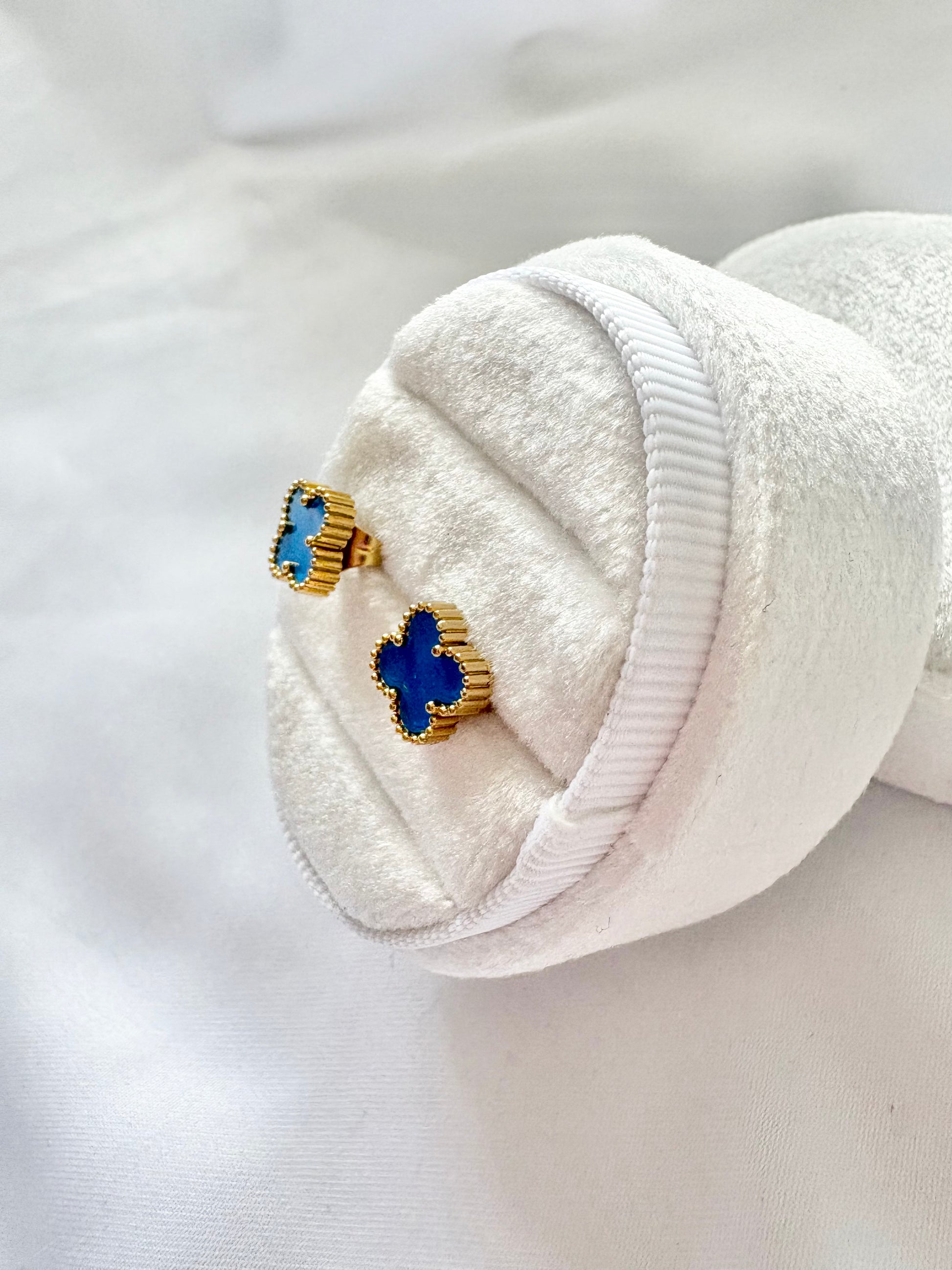 Blue and gold earrings in a white jewelry box on a white background