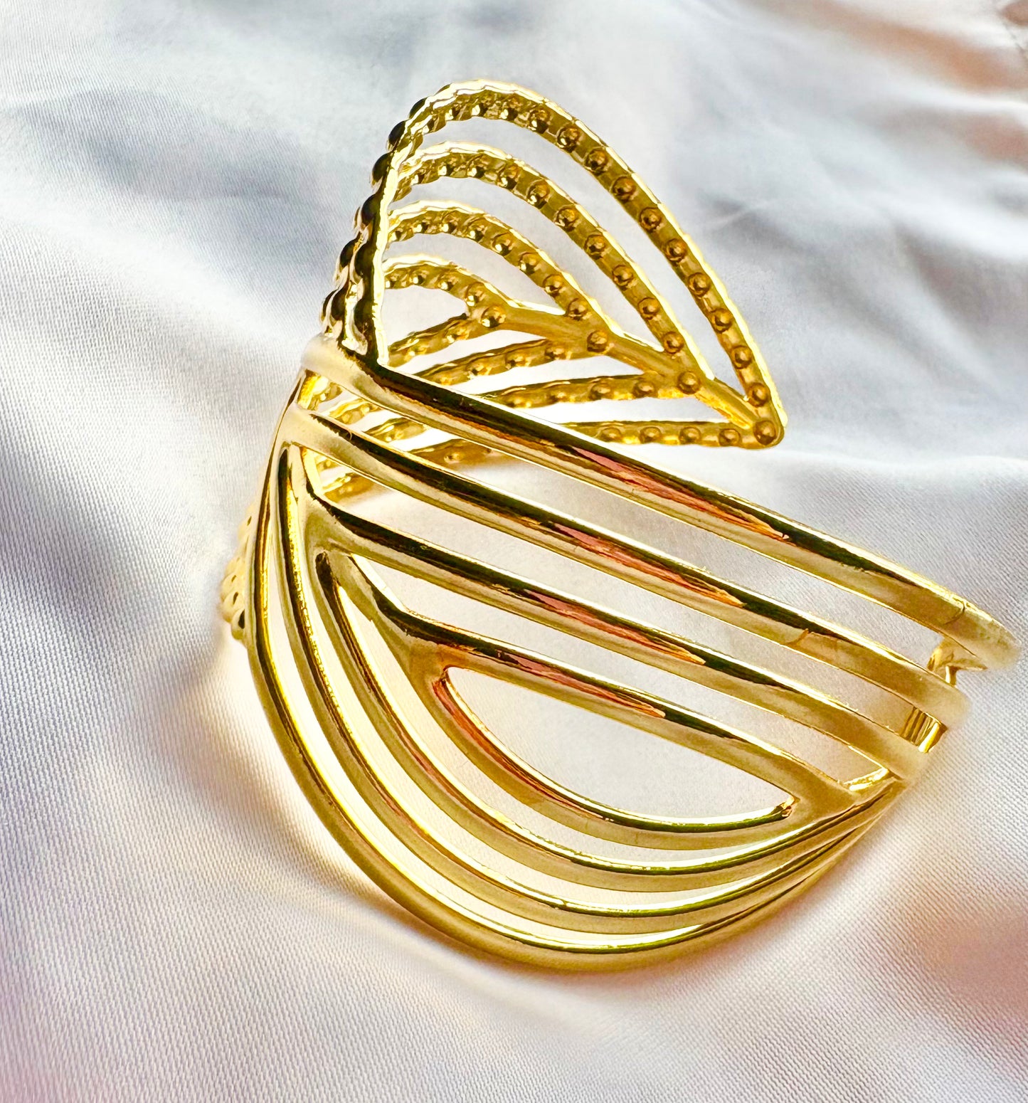 Gold leaf-shaped bangle on a white fabric background