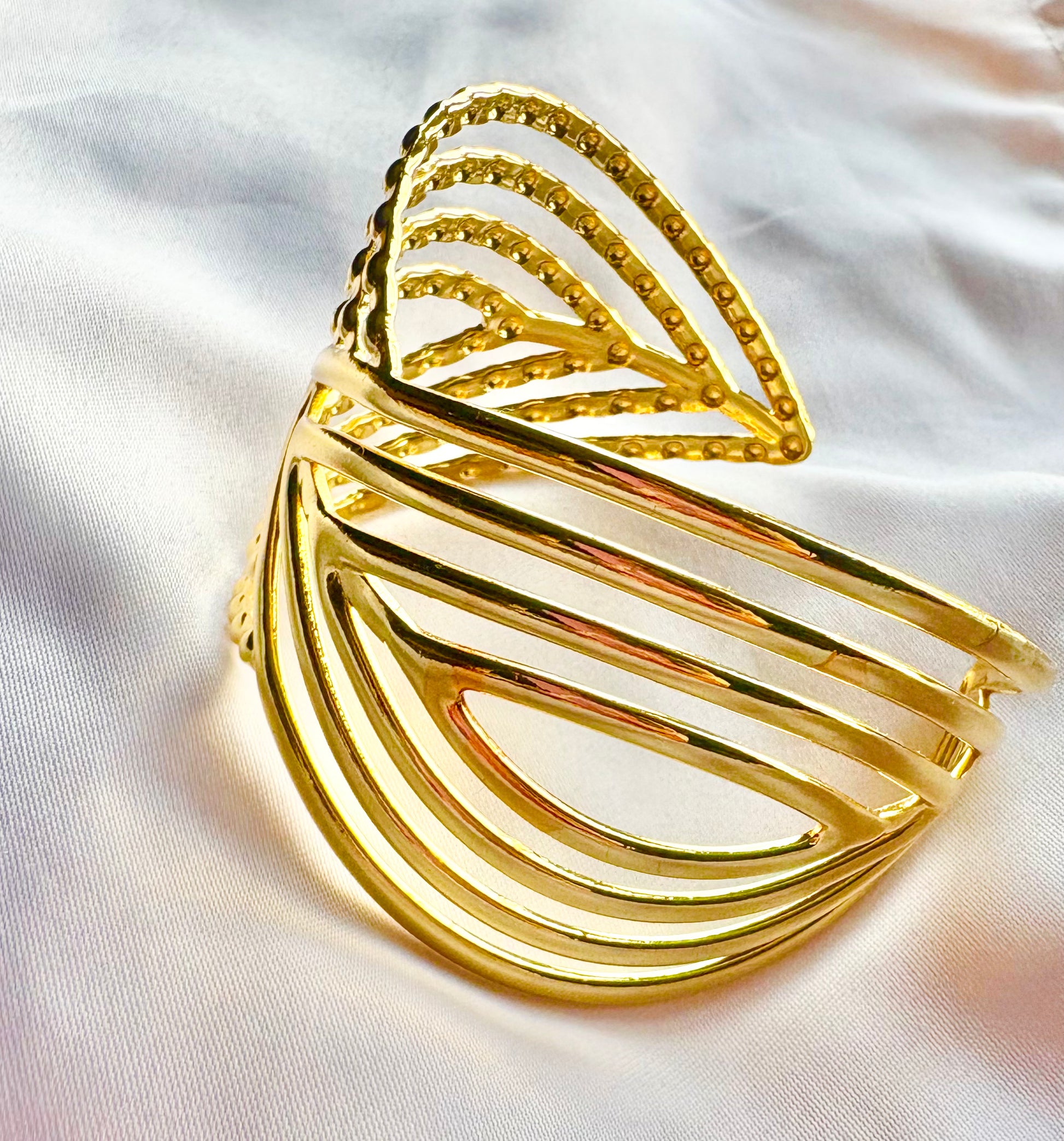 Gold leaf-shaped bangle on a white fabric background