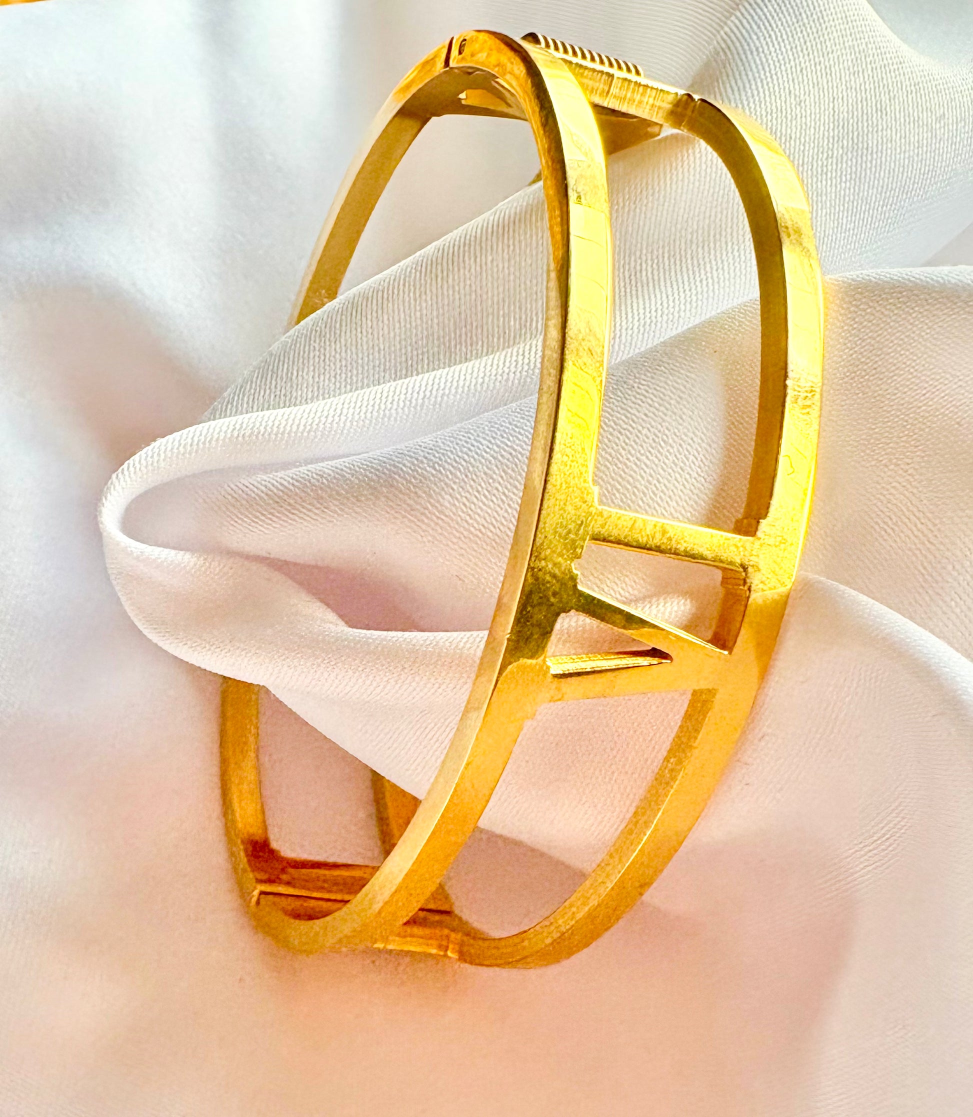 Gold bracelet on a soft white fabric background